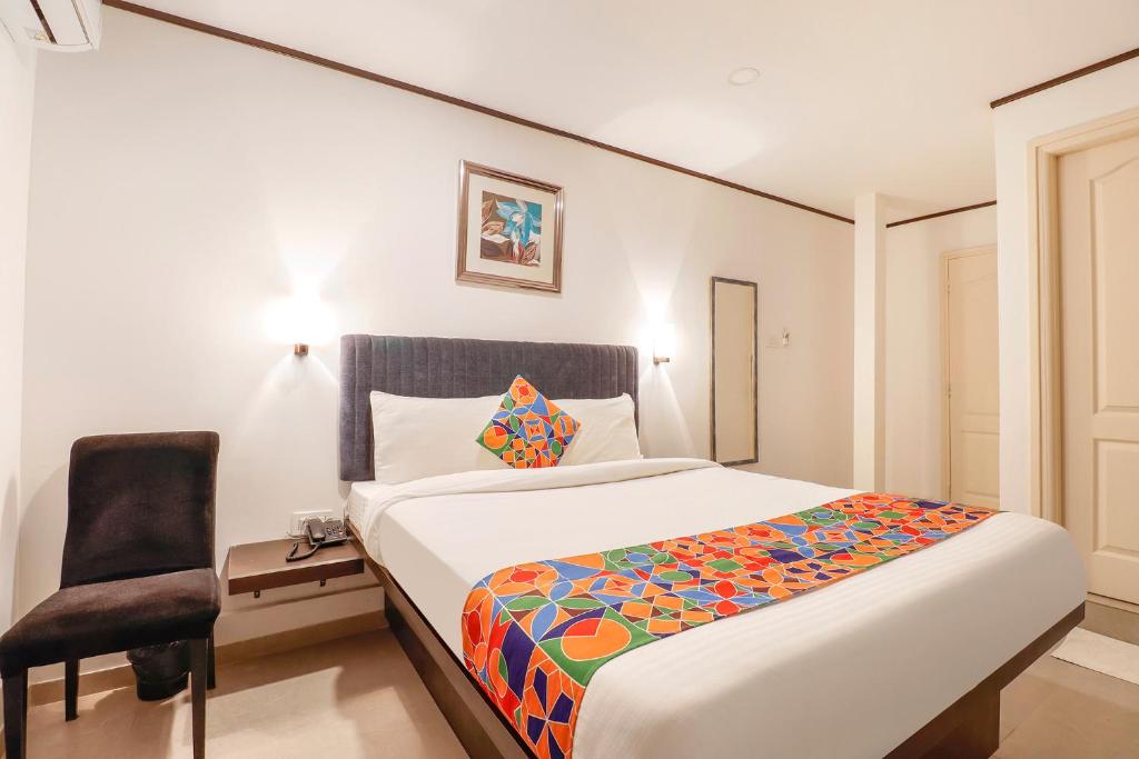バンガロールにあるFabHotel Park Inn Indiranagarのベッドと椅子付きのホテルルーム