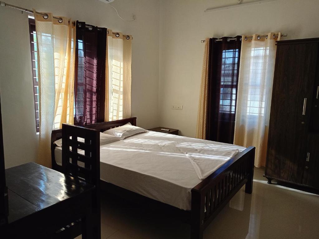 a bedroom with a bed and two windows at Enna homestay in Varkala