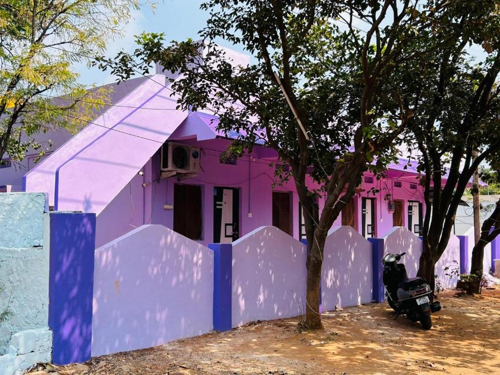 une maison violette avec une moto garée devant elle dans l'établissement Hotel R residence, à Srīsailam