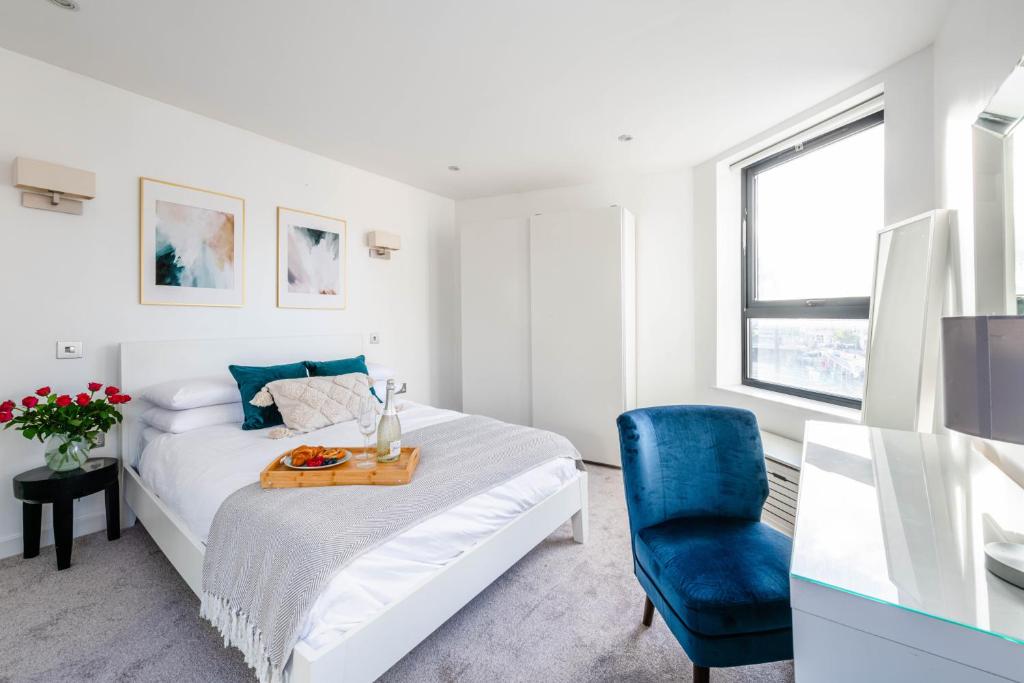 a white bedroom with a bed and a blue chair at Stunning 1 Bed apartment Kings Cross/St Pancras Farringdon in London