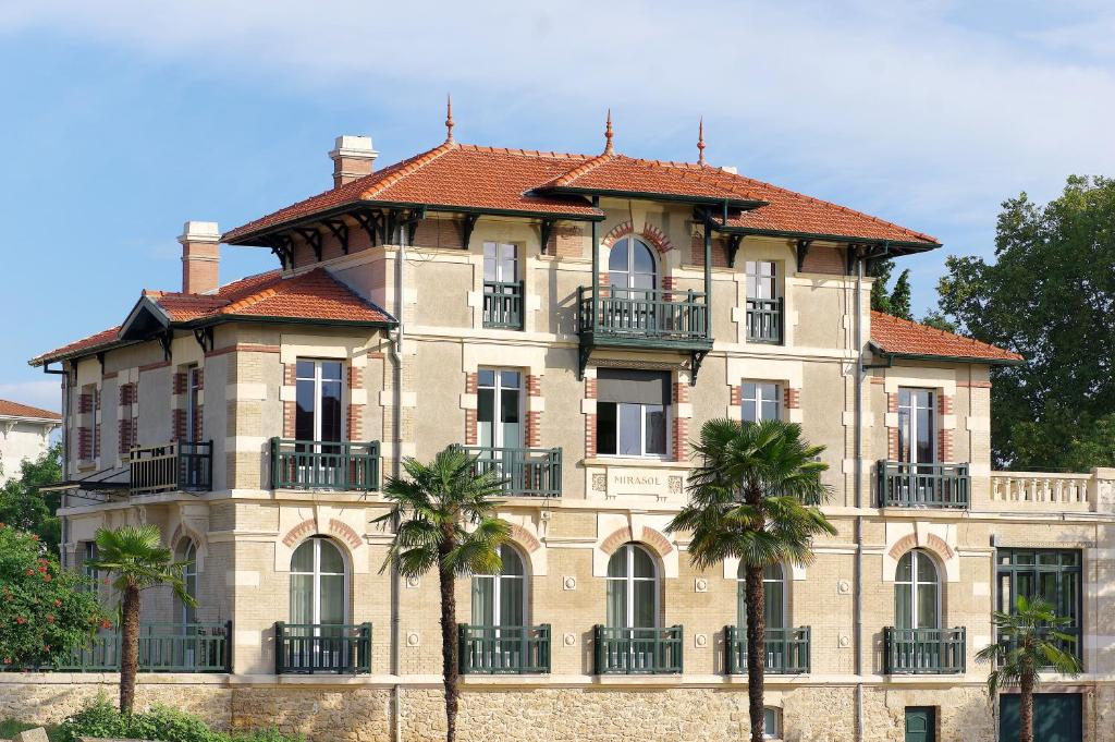 un grand bâtiment avec des palmiers devant lui dans l'établissement Villa Mirasol, à Mont-de-Marsan
