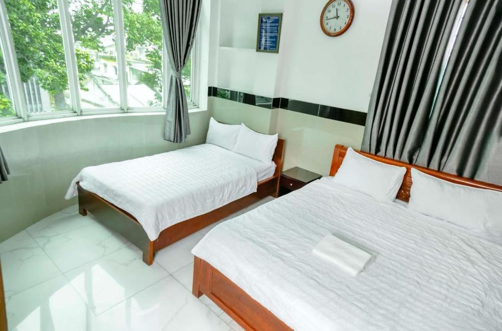 a room with two beds and a clock on the wall at THANH NGỌC HOTEL in Ho Chi Minh City