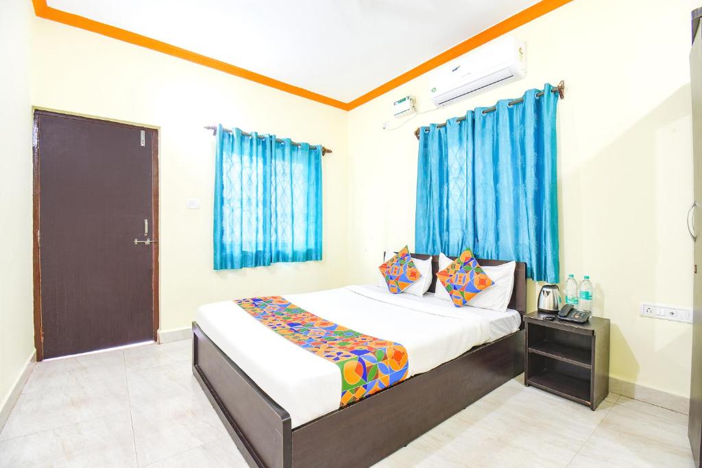 FabExpress Shanel Beachside Resort في باغا: غرفة نوم بسرير والستائر زرقاء