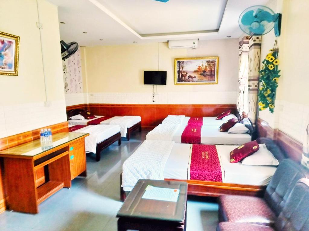 una camera d'albergo con 3 letti e una scrivania di GRAD Hoa Do Hotel a Xuân Ðài