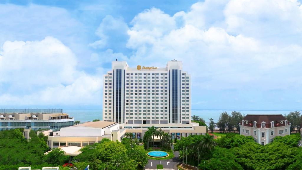 un grand bâtiment blanc avec des arbres devant lui dans l'établissement Shangri-La Beihai, à Beihai