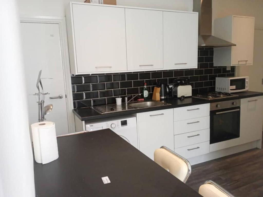 une cuisine avec des placards blancs et un comptoir noir dans l'établissement Double bed (R1) close to Burnley city centre, à Burnley