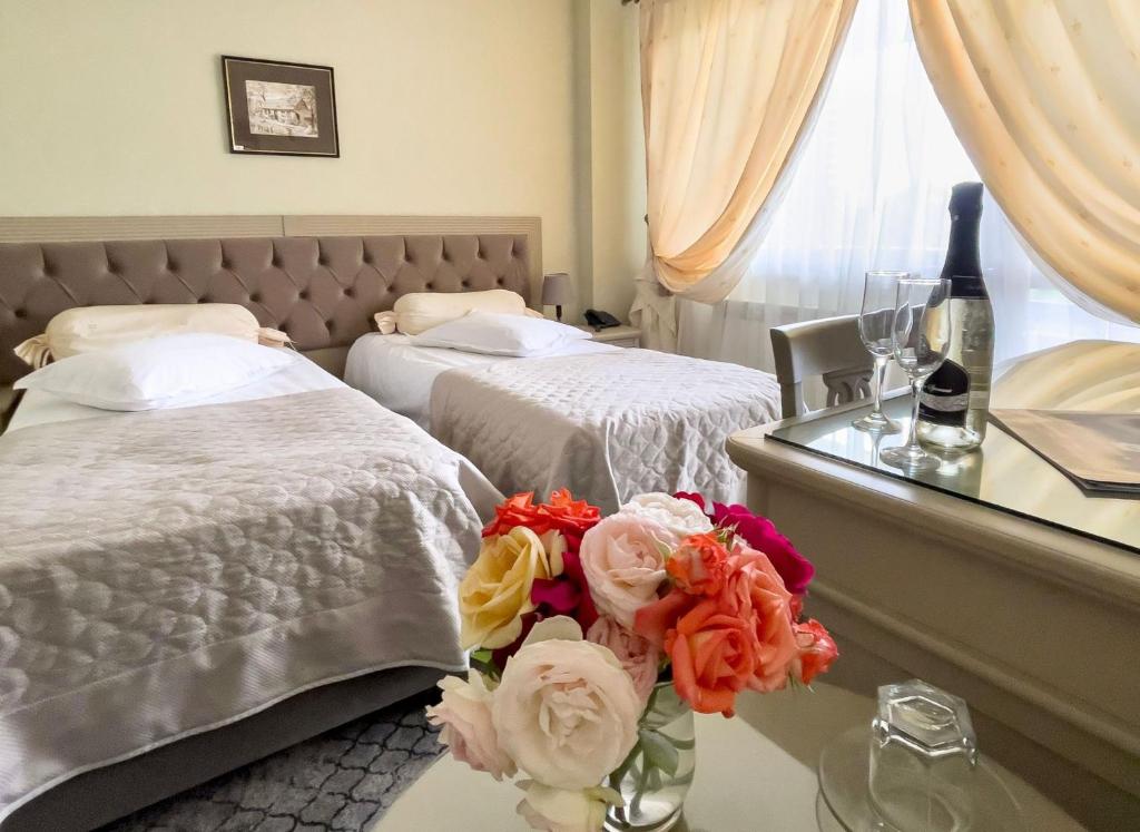 a hotel room with two beds and a table with flowers at Bucium Motel & SPA in Iaşi