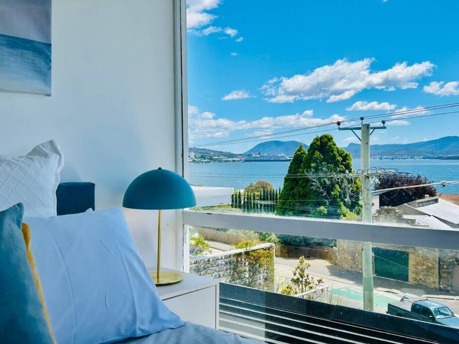 a bedroom with a large window with a view of the water at The Tassie - Luxury with panoramic water views in Hobart
