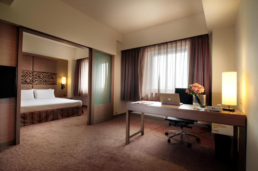 a hotel room with a bed and a desk with a laptop at Howard Civil Service International House in Taipei
