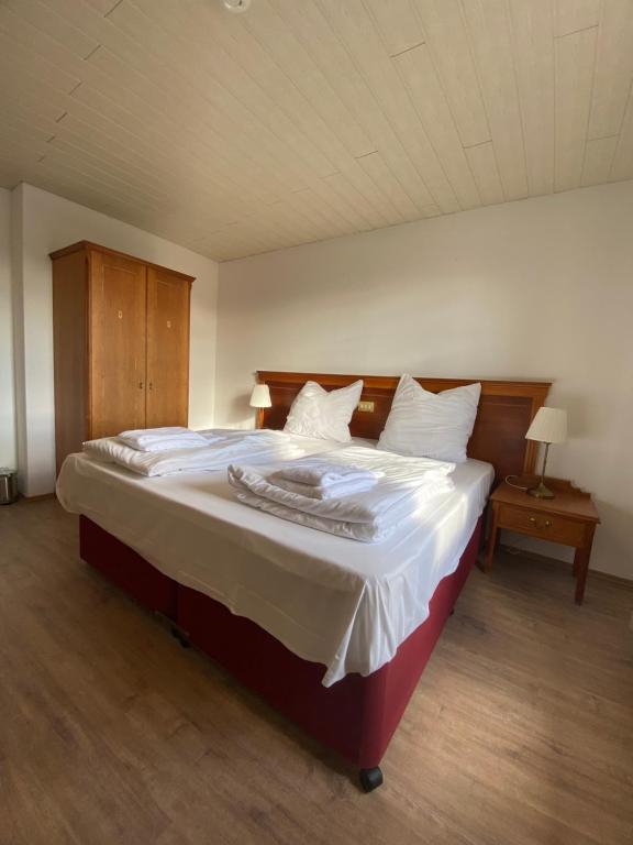 um quarto com uma cama grande e lençóis brancos em Hotel Vienenburg em Goslar