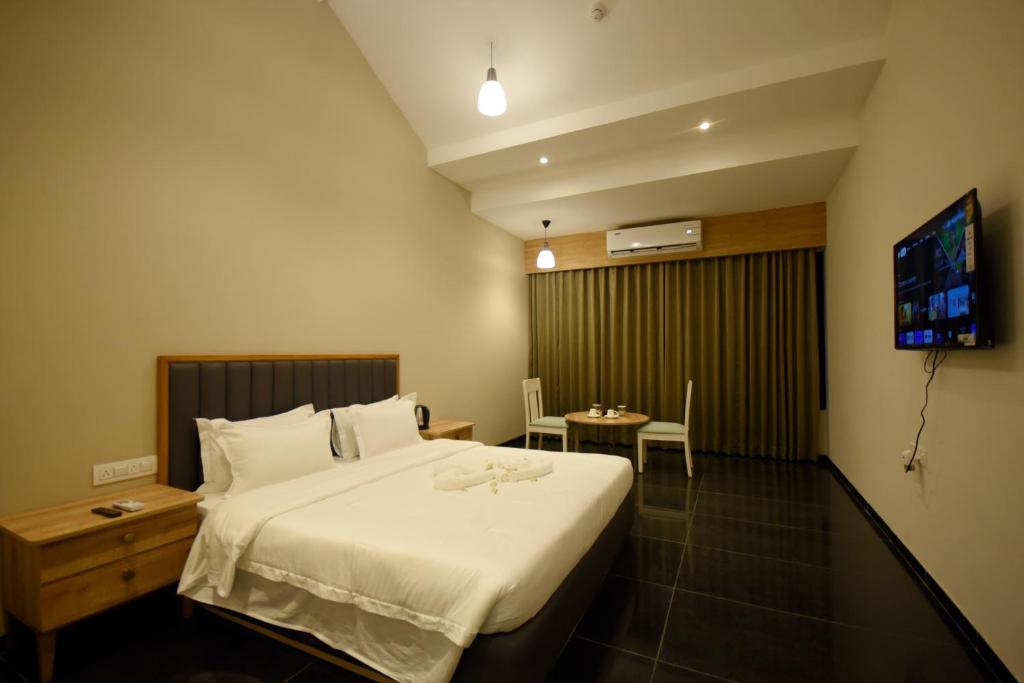 a hotel room with a large bed and a table at The Daman Club in Daman