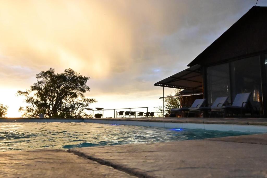 a swimming pool in front of a house at Aloegrove Safari Lodge in Otjiwarongo