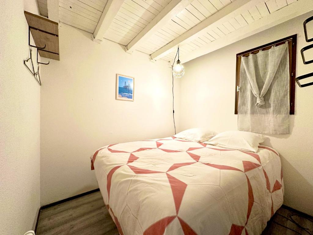 um quarto com uma cama com um edredão vermelho e branco em Le repaire des voyageurs em Port Leucate