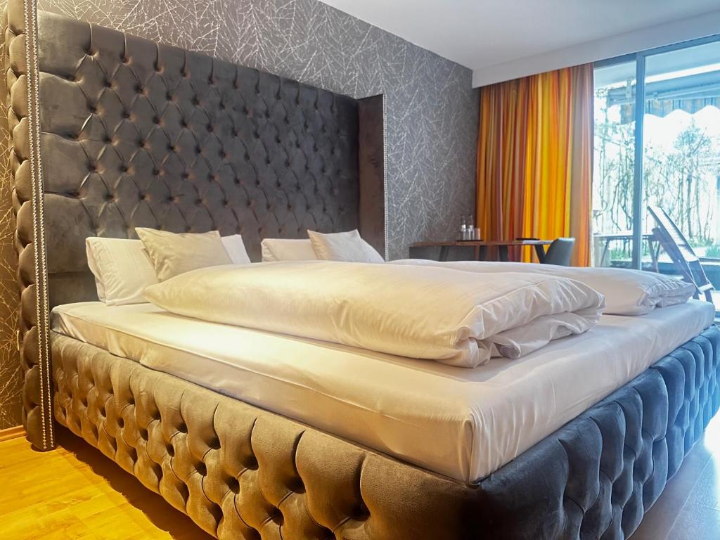 a large bed with a large padded headboard in a bedroom at Hotel Unterfeldhaus in Erkrath