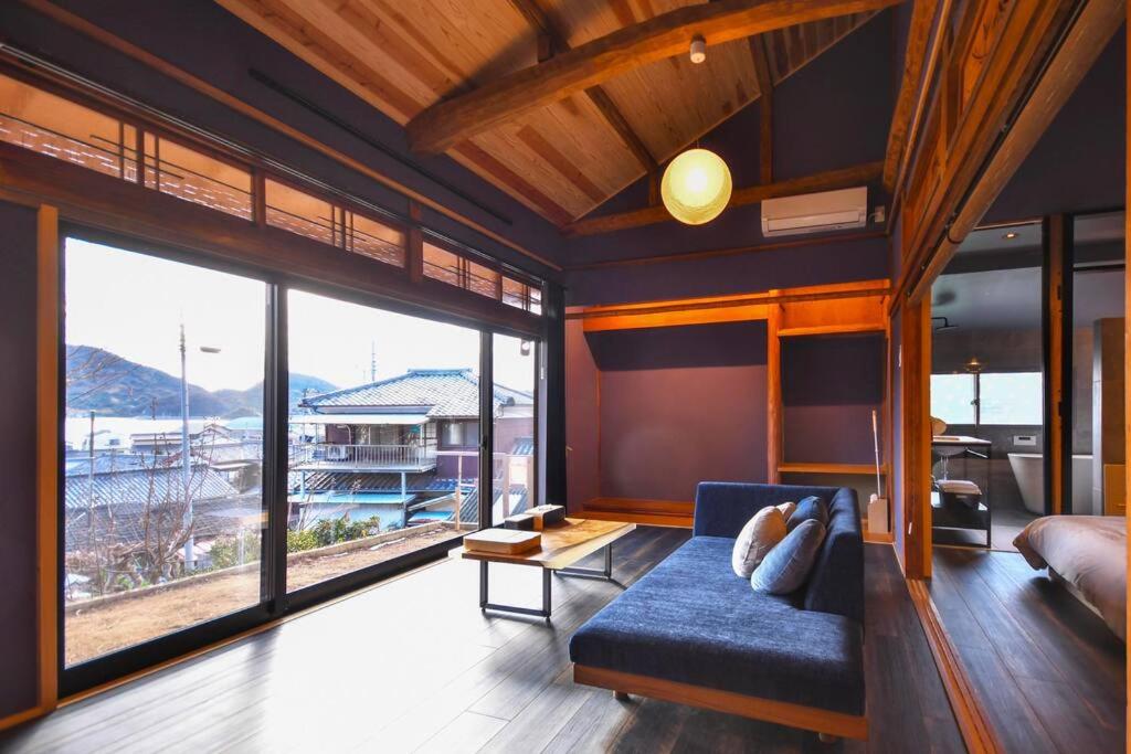 a living room with a blue couch and large windows at 由良民泊島宿 in Matsuyama