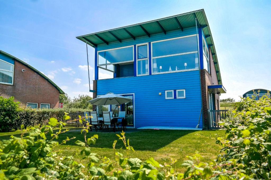 una casa azul con techo verde en 6pers. Lauwersmeer Lakefront. Nirvana house with sauna, pellet stove, en Anjum