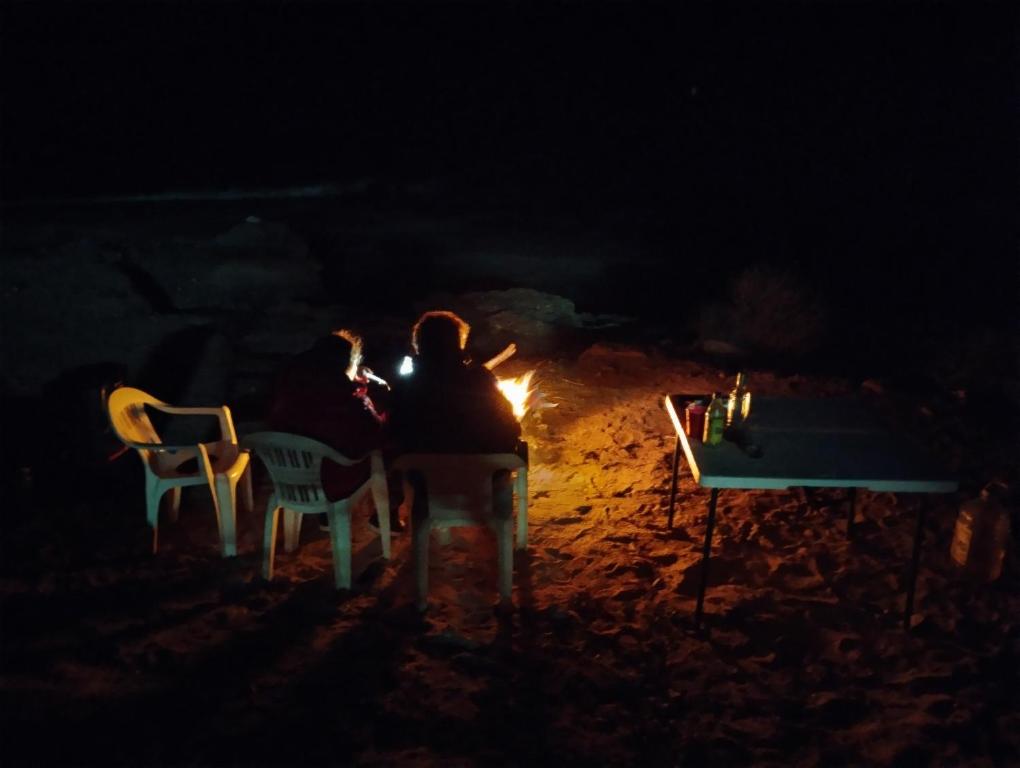 a group of people sitting around a fire at night at Mag Bay Paradise in San Carlos