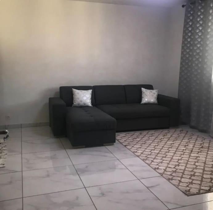 uma sala de estar com um sofá preto e um tapete em Appartement au RDC d’une maison em Privas