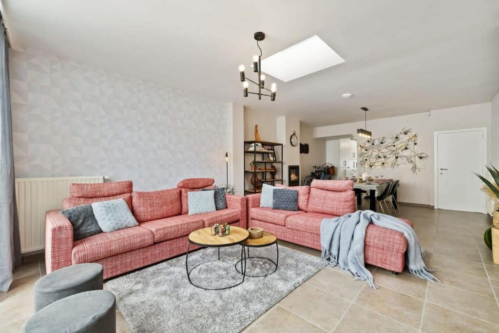 ein Wohnzimmer mit 2 rosa Sofas und einem Tisch in der Unterkunft Spacious house with 3 terraces in Nieuwpoort
