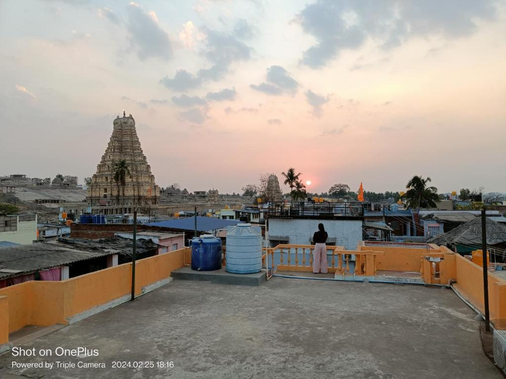 un hombre parado en un techo mirando un templo en Vicky's Home Stay Hampi, en Hampi