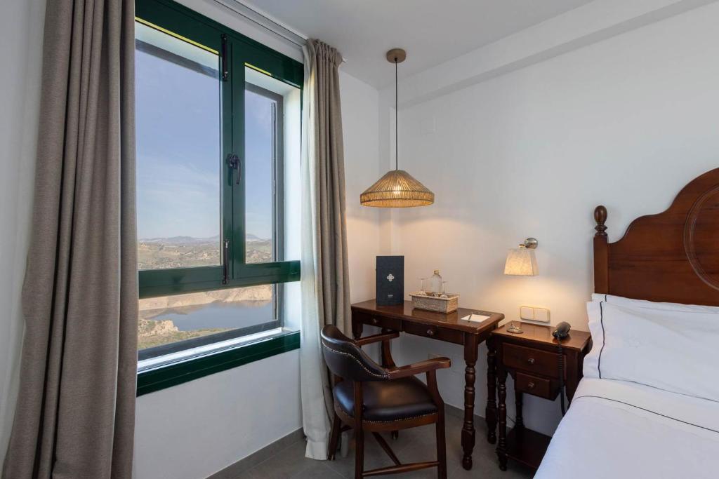 a bedroom with a desk and a bed and a window at Hotel Tugasa Arco de la Villa in Zahara de la Sierra