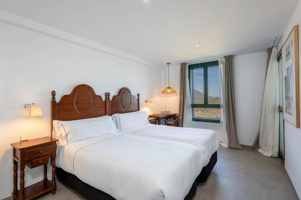 a bedroom with a large white bed and a window at Hotel Tugasa Arco de la Villa in Zahara de la Sierra