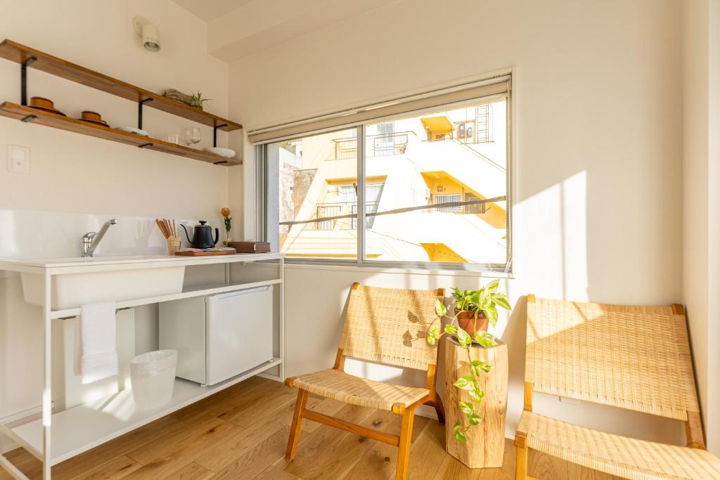 eine Küche mit einem Tisch, 2 Stühlen und einem Fenster in der Unterkunft hotel & cafe ksnowki in Dejimamachi