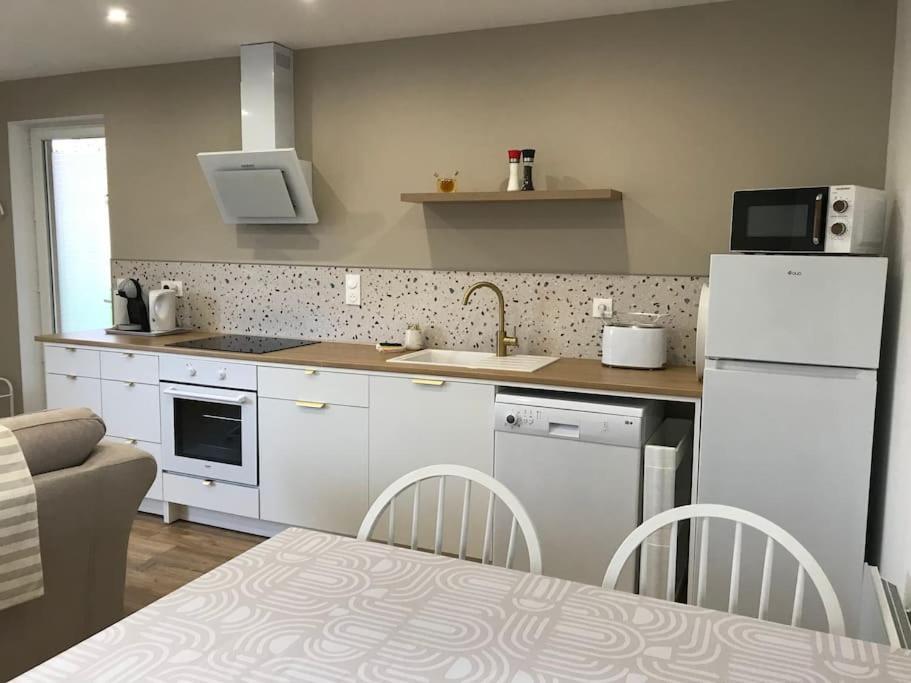 une cuisine avec un réfrigérateur blanc et une table dans l'établissement Gîte 2 chambres tout confort, à Tournon-Saint-Pierre