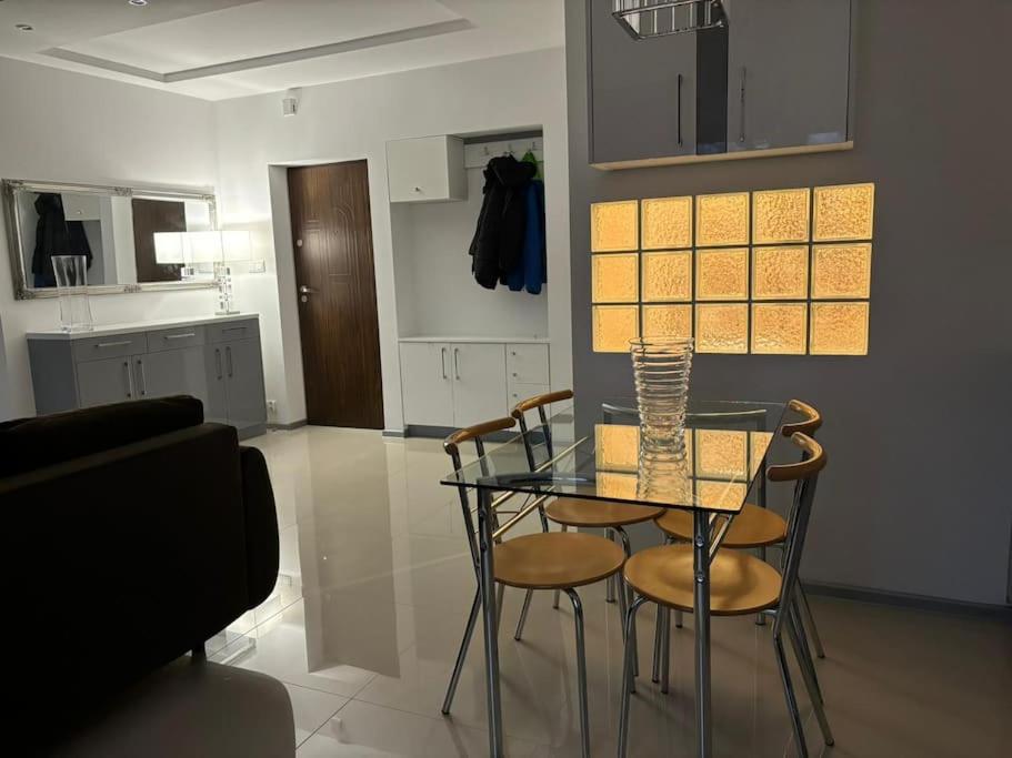 uma sala de jantar com uma mesa de vidro e cadeiras em Centrum atrakcyjne mieszkanie em Bialystok