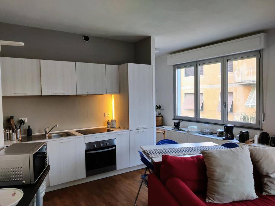 uma cozinha com armários brancos e um sofá vermelho em Rainbow Suite Pisa em Pisa
