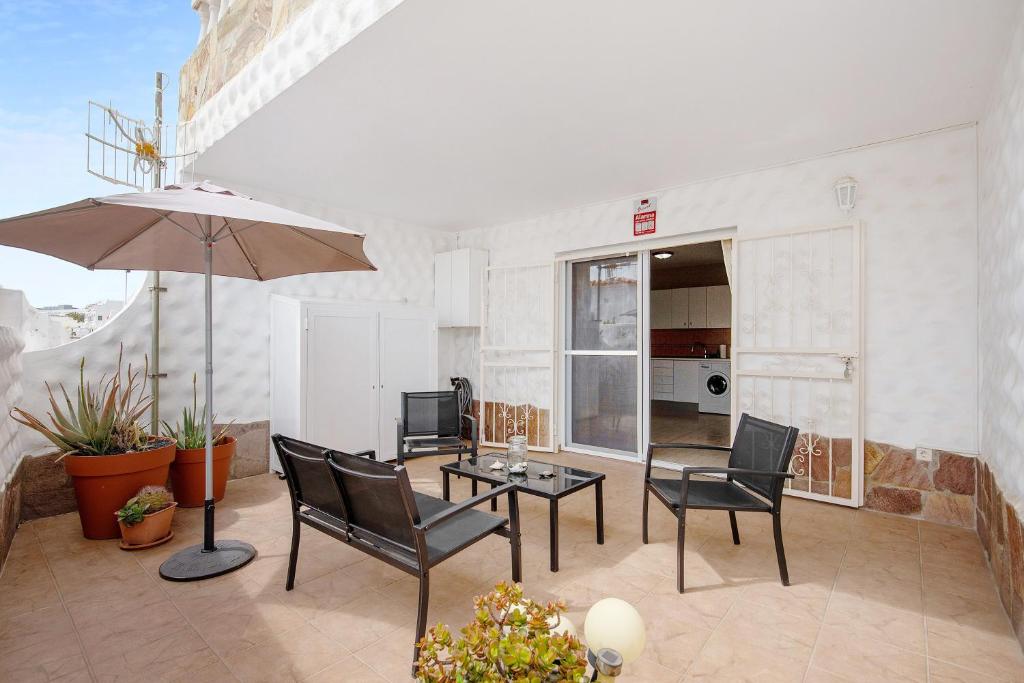 a patio with a table and chairs and an umbrella at Casa Weimar in Costa Calma
