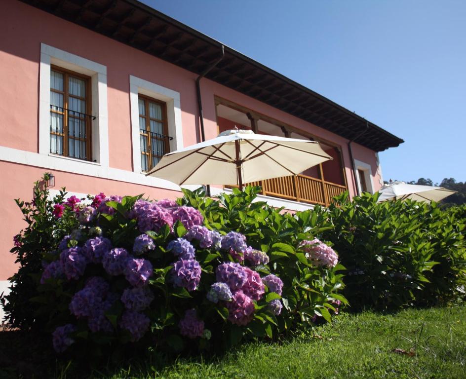 an umbrella and flowers in front of a building at Hotel Puerta Del Oriente in Tresgrandas