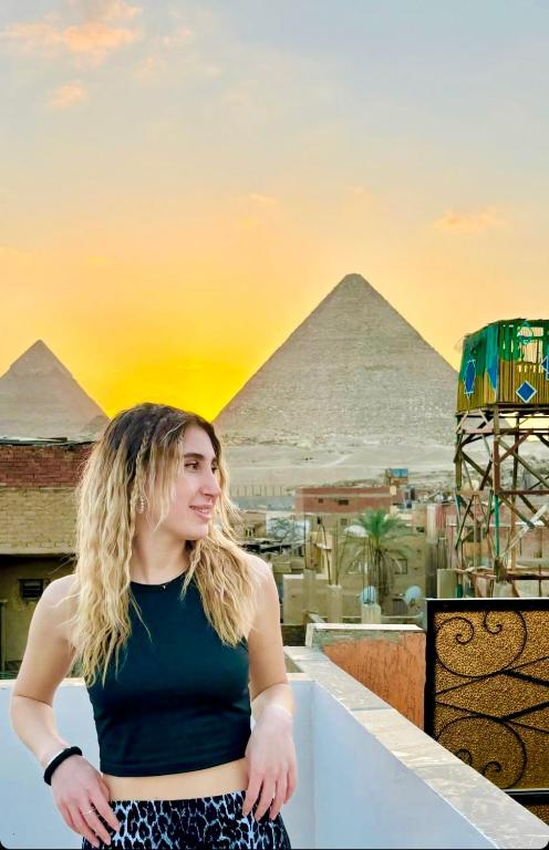 a woman standing on a ledge with the pyramids in the background at Horus pyramids view in Cairo