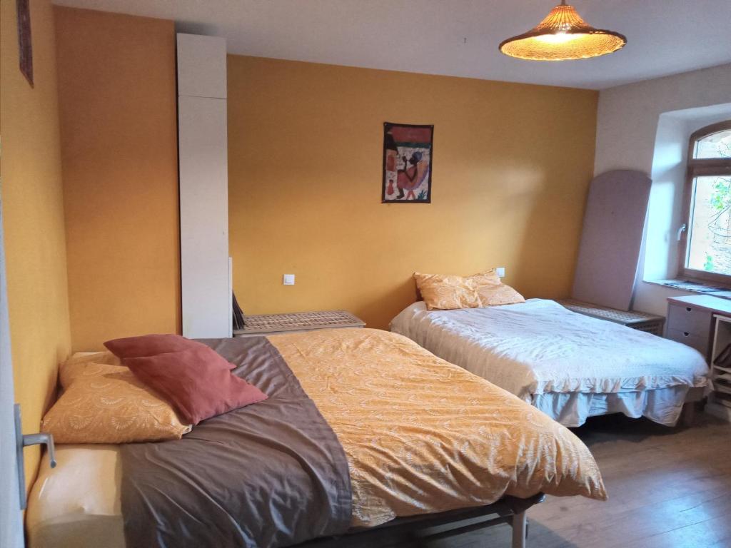 2 camas en una habitación con paredes amarillas en Le Puech et vous en Saint-André-de-Majencoules