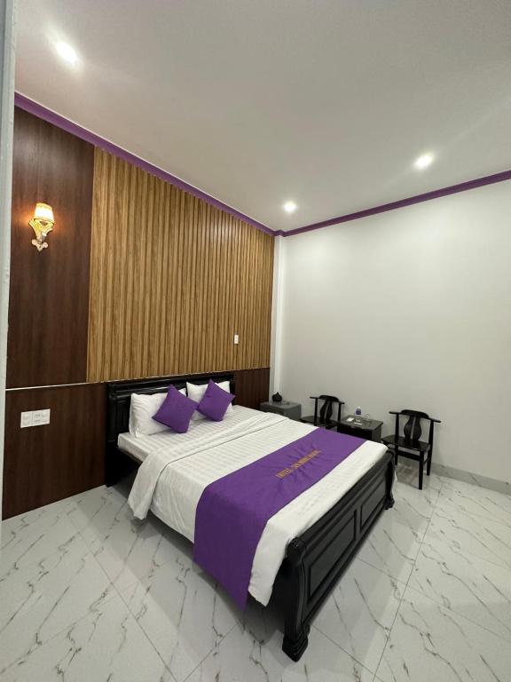 1 dormitorio con 1 cama grande con almohadas moradas en Minh Hoàng Hotel & Spa - Phan Thiết en Ấp Bình Hưng