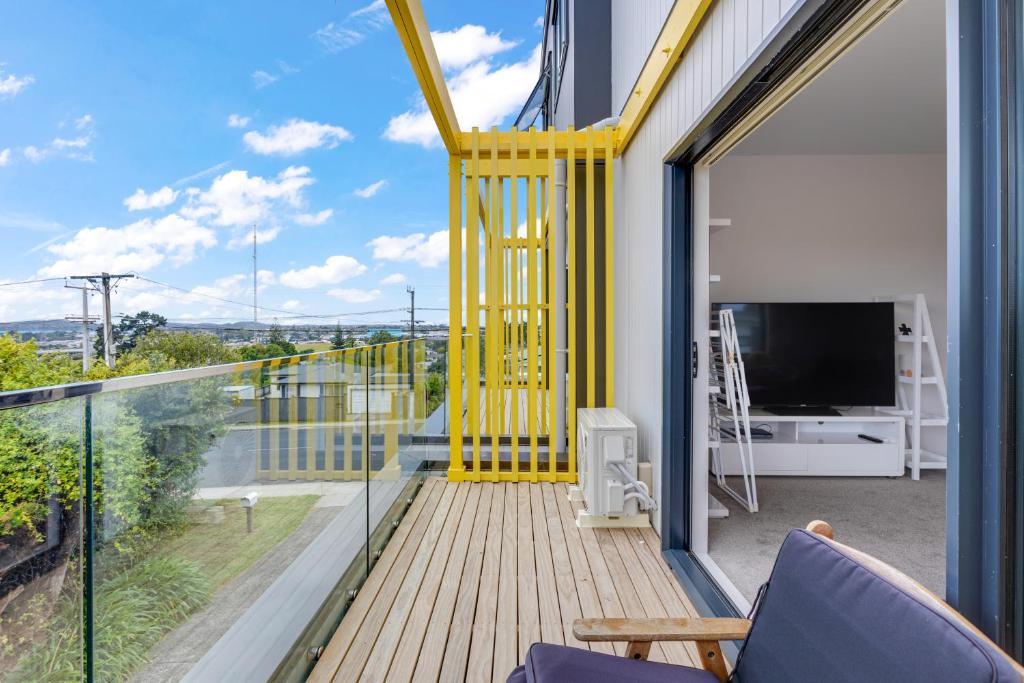 a balcony with a yellow railing and a tv at Sleek Vista Townhouse with deck and air-con in Auckland