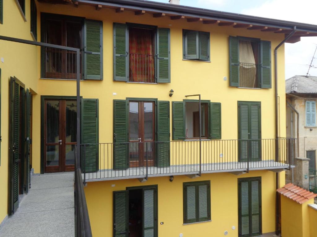 un edificio amarillo con persianas verdes y balcón en La Corte B&B, en Fagnano Olona