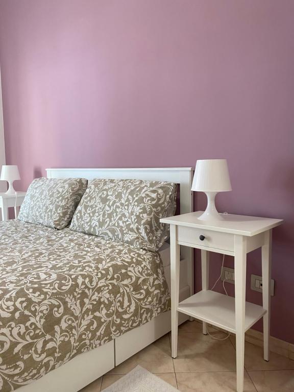 a bed with a night stand next to a white table with a lamp at Casa Vacanze Marzia in Rome