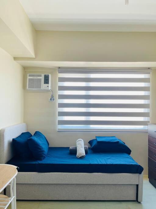 a bed with blue pillows in a room with a window at * *H2 Modern City Condo in Iloilo City