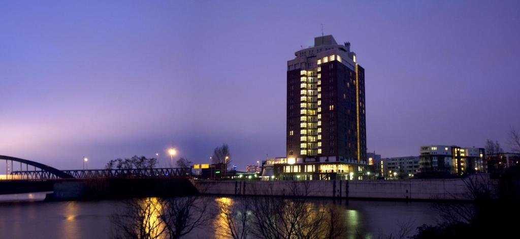 a tall building with a bridge next to a river at HI Hotel International Hamburg in Hamburg