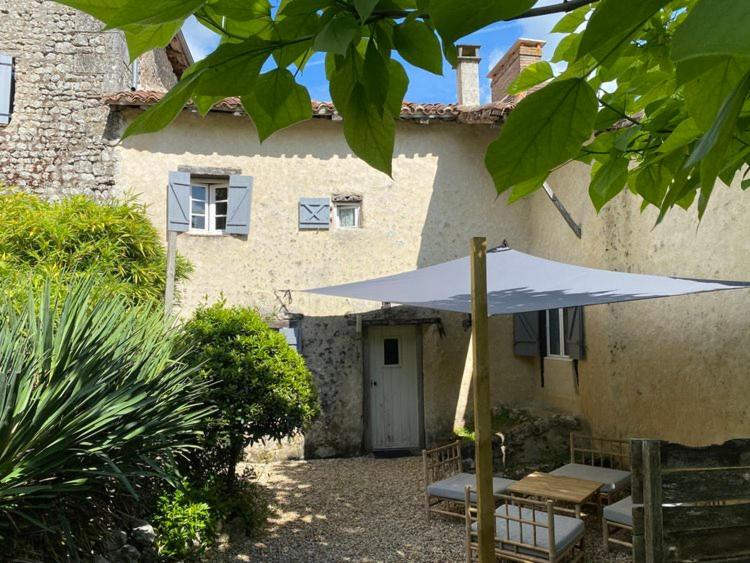 eine Terrasse mit einem Tisch und einem Sonnenschirm vor einem Gebäude in der Unterkunft Maison d'Amis in Salles-Lavalette