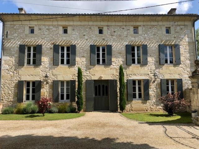 a large stone house with black windows and a driveway at Domaine des Monges in Saint-Seurin-de-Prats