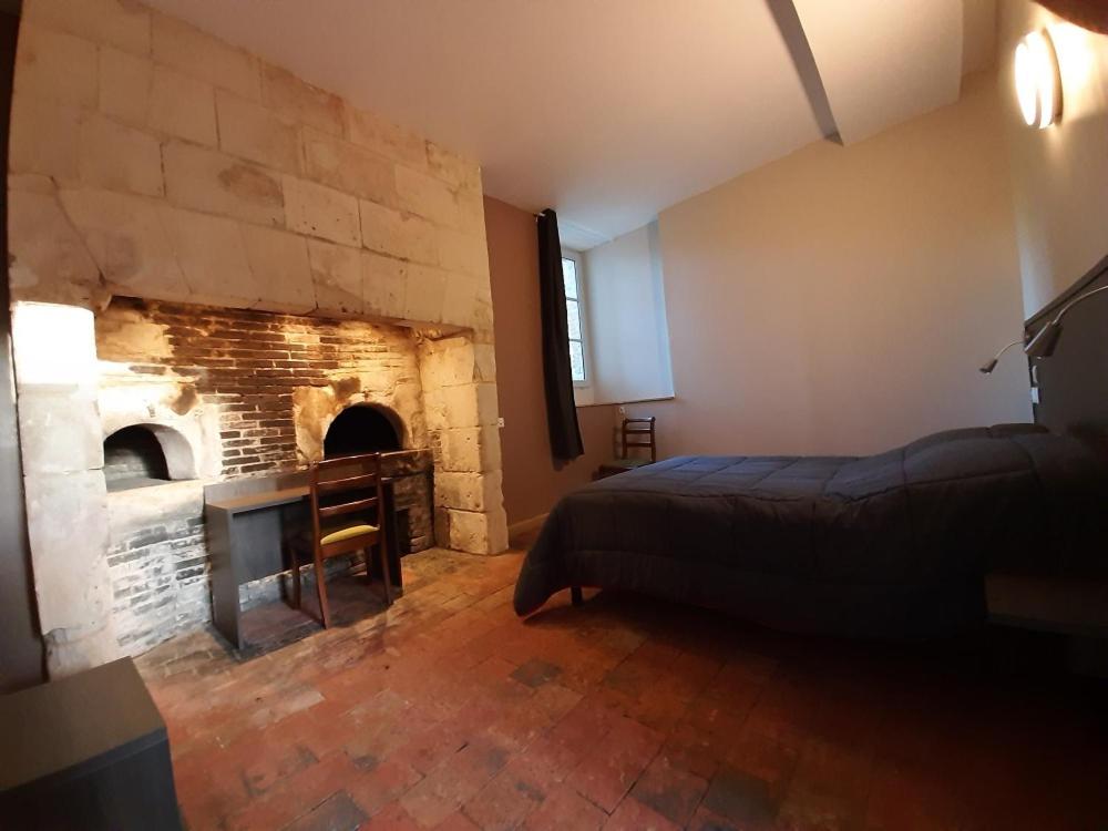 Schlafzimmer mit einem Bett und einem Steinkamin in der Unterkunft Chambre au château de Grésillon in Saint-Martin-dʼArcé