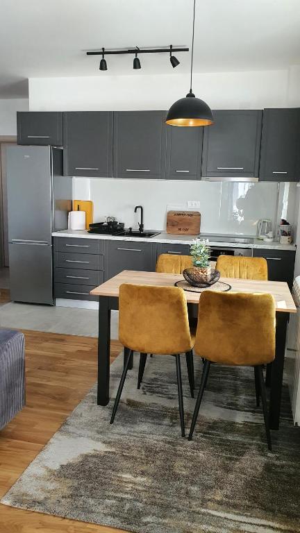 a kitchen with a table and chairs in a room at JR Lux apartman in Stara Pazova