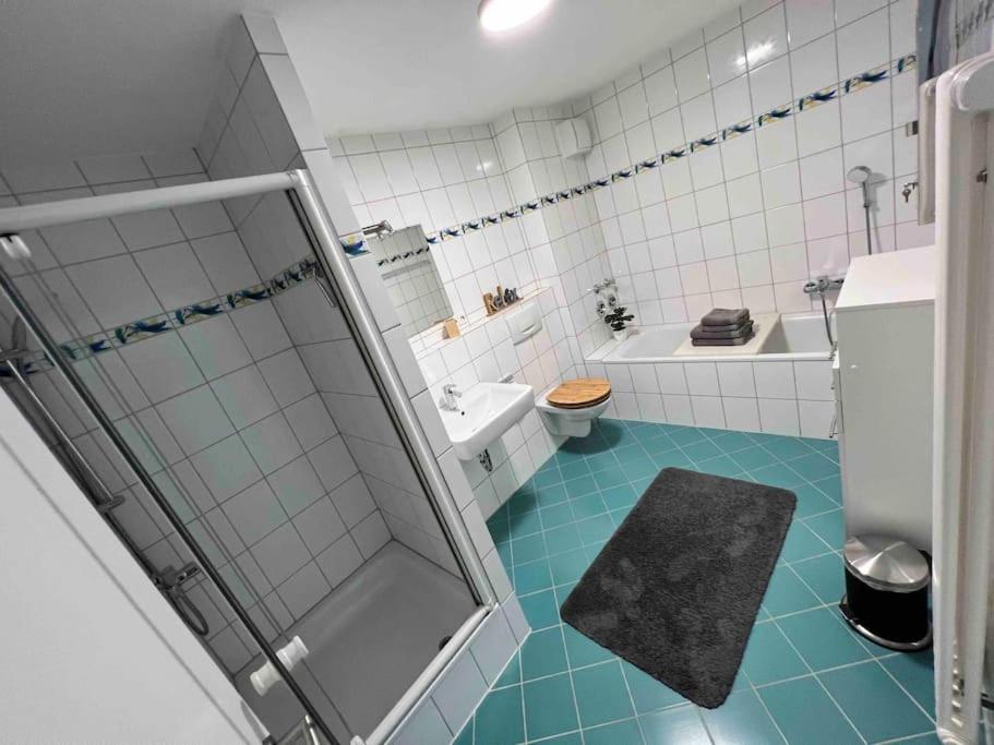 ein Bad mit Dusche und blauem Boden in der Unterkunft Tobi‘s Ferienapartment in Gottmadingen
