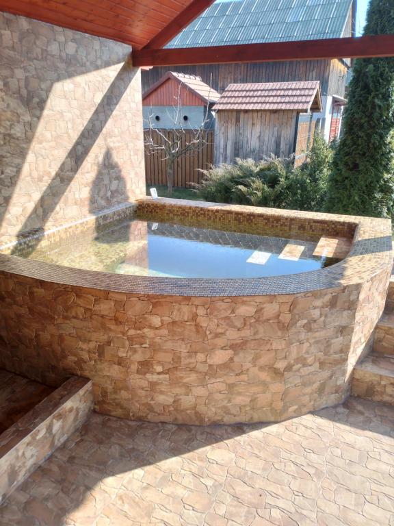 a pool in a stone retaining wall with a water feature at Timi Kulcsosház in Lăzarea