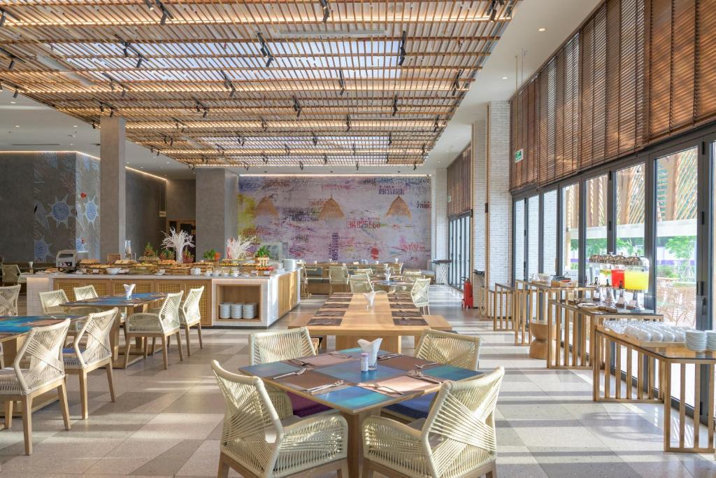 a dining room with tables and chairs and windows at TTC Van Phong Bay Resort - Himalaya Sauna & Steam Retreat Included in Ninh Hòa