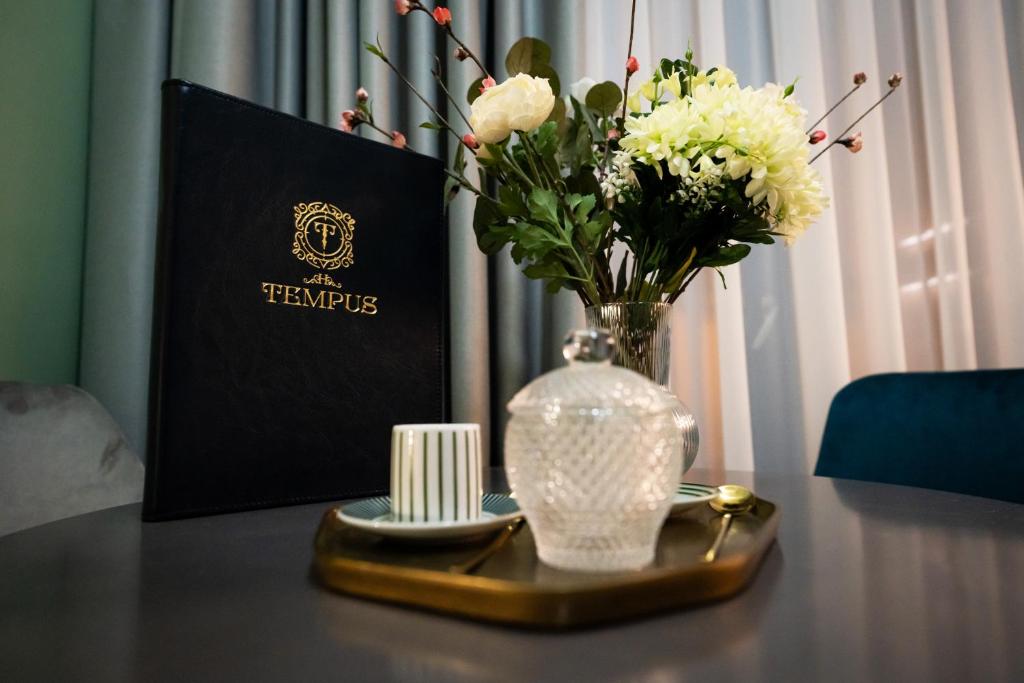 a table with a vase of flowers and a plate at Tempus in Bucharest