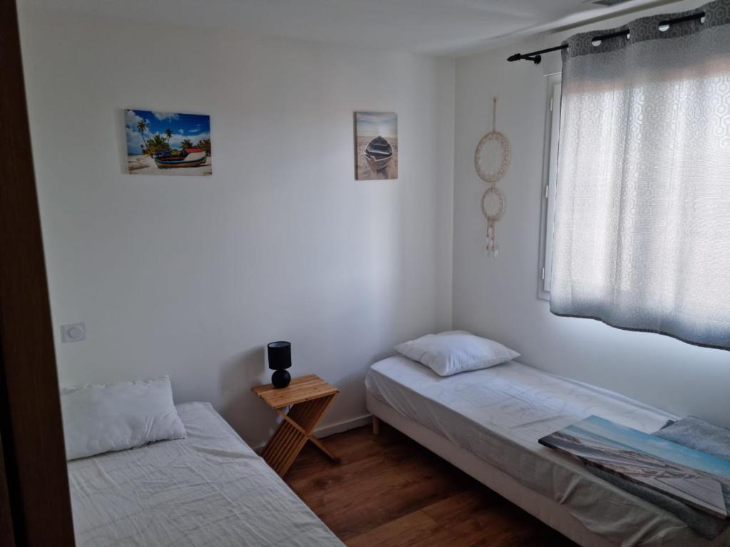 um quarto com 2 camas e uma janela em SAINT CYPRIEN Moderne 4 chambres et jardin em Saint-Cyprien
