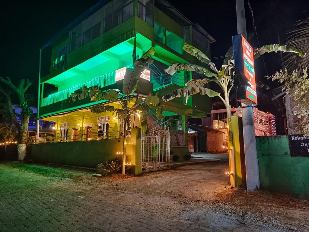 um edifício verde com uma árvore em frente em JUNGLE STAR MANSION em Kaziranga